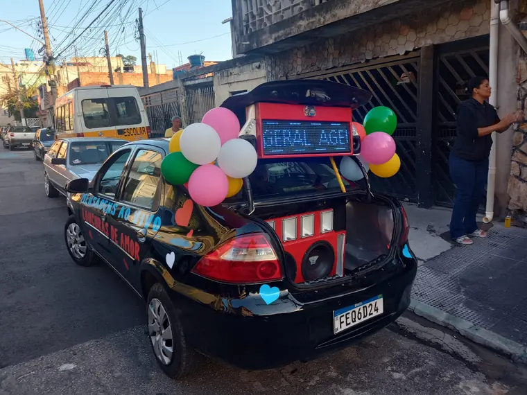 Traseira do carro de som com balões e letreiro digital aceso ao entardecer