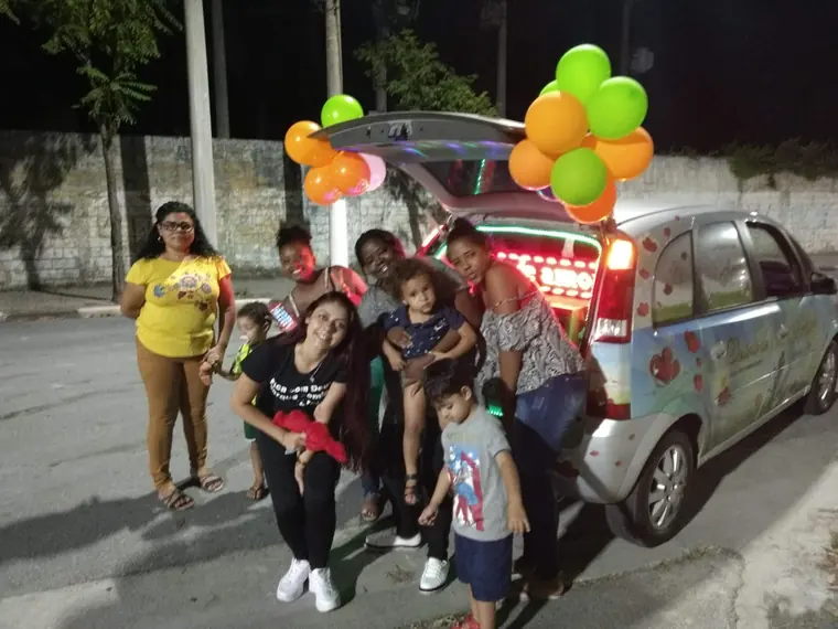Crianças e adultos posando ao lado do carro decorado com balões
