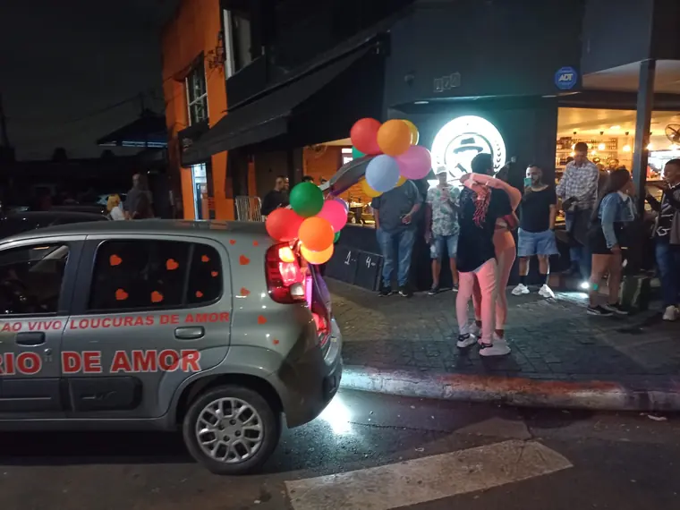 Vizinhos parados na calçada assistindo à homenagem do carro de som