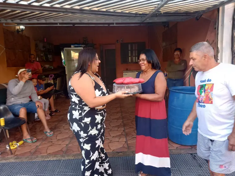 Entrega de presente e bolo para a homenageada na calçada
