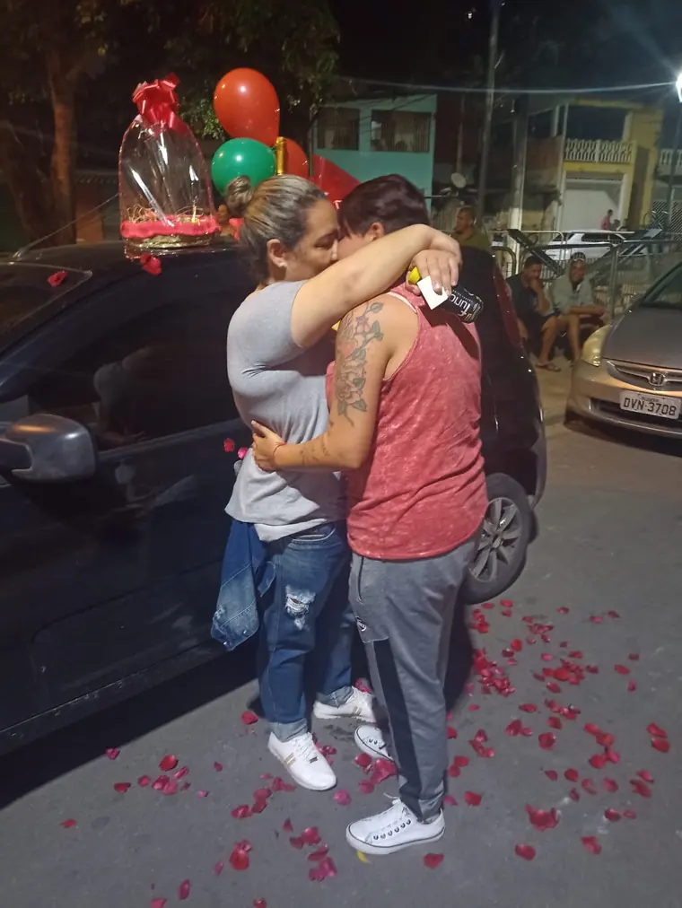 Casal abraçado na rua com pétalas de rosa no chão